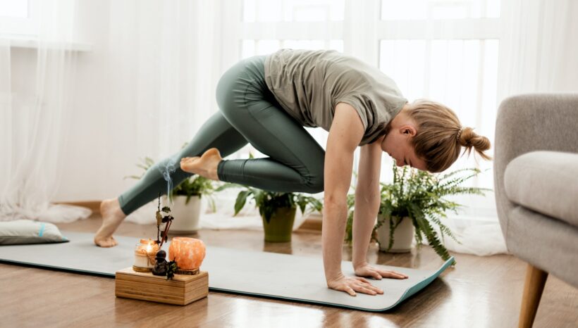 Beautiful young woman doing exercises and doing yoga at home